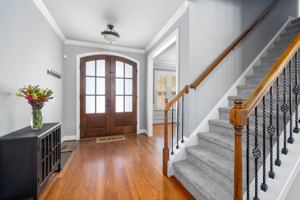 Beautiful home foyer with wooden door, staircase, and decor, perfect for showcasing interior design.